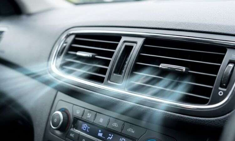 Close-up of car air conditioning vents blowing cold air inside vehicle cabin dashboard
