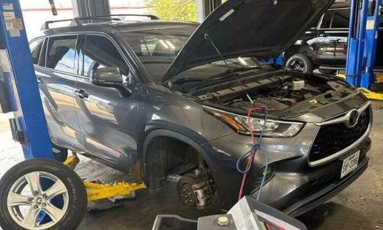 Auto mechanic using pressure gauges to test car AC system refrigerant levels during service